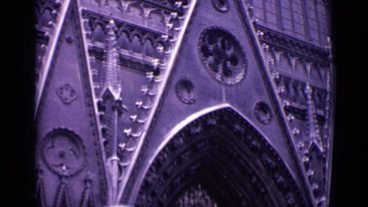 Close view of a Gothic cathedral facade with pointed arch, tracery and circular stone details at night.