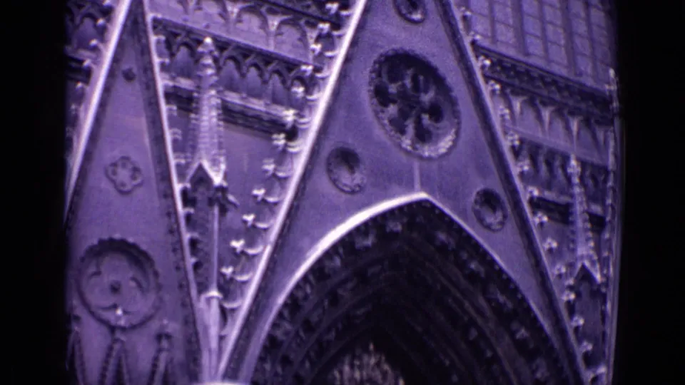 1962 German 8mm view of Gothic cathedral stonework, showing a pointed arch, decorative tracery and circular facade details under night lighting.