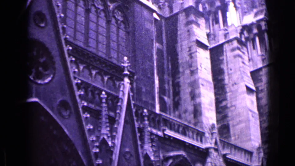 1962 Germany travel footage frame with an angled view of Gothic cathedral architecture, including tracery, buttress-like stonework and upper facade details.