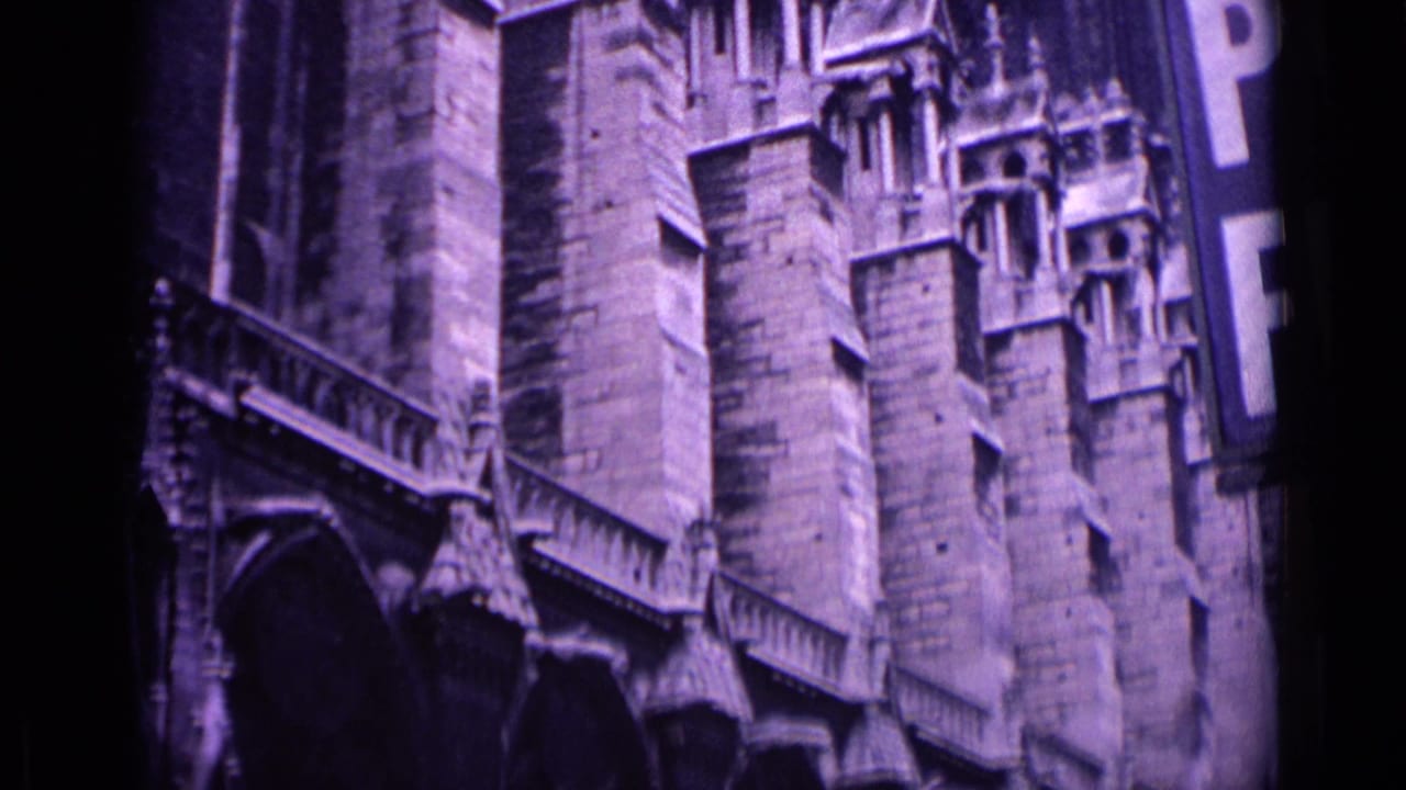 1962 Germany home-movie frame showing a Gothic church facade with stone buttresses, pointed arches, and a cropped vertical sign.