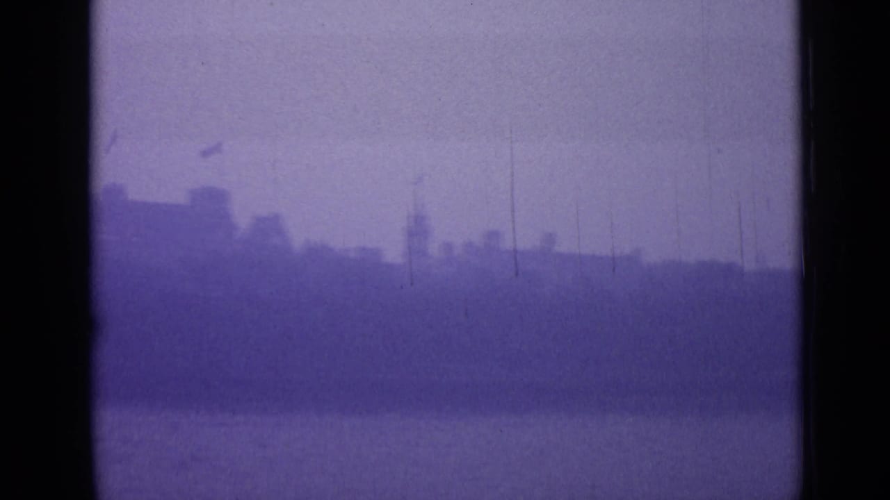 Foggy skyline across water with dark building silhouettes and visible film border.