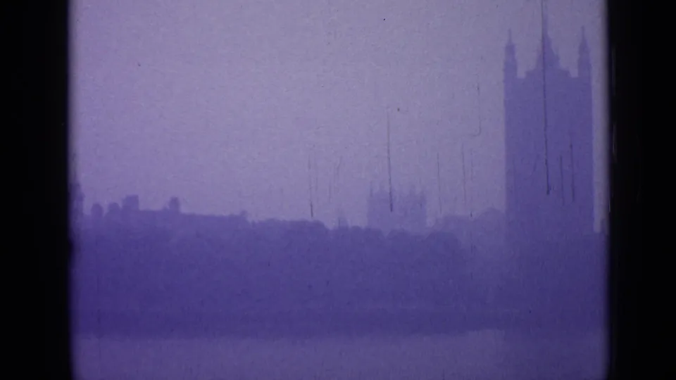 Fog-muted London buildings stretch across the lower frame, with a partial tall tower visible near the right edge of the 8mm scan.