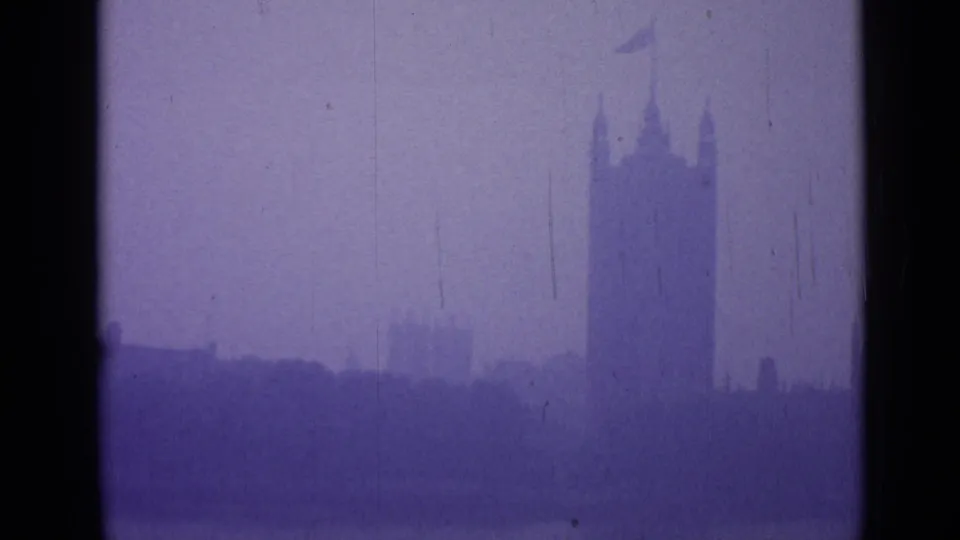 A tall London tower with a small flag is silhouetted in fog above the waterfront, framed by soft purple 8mm film color.