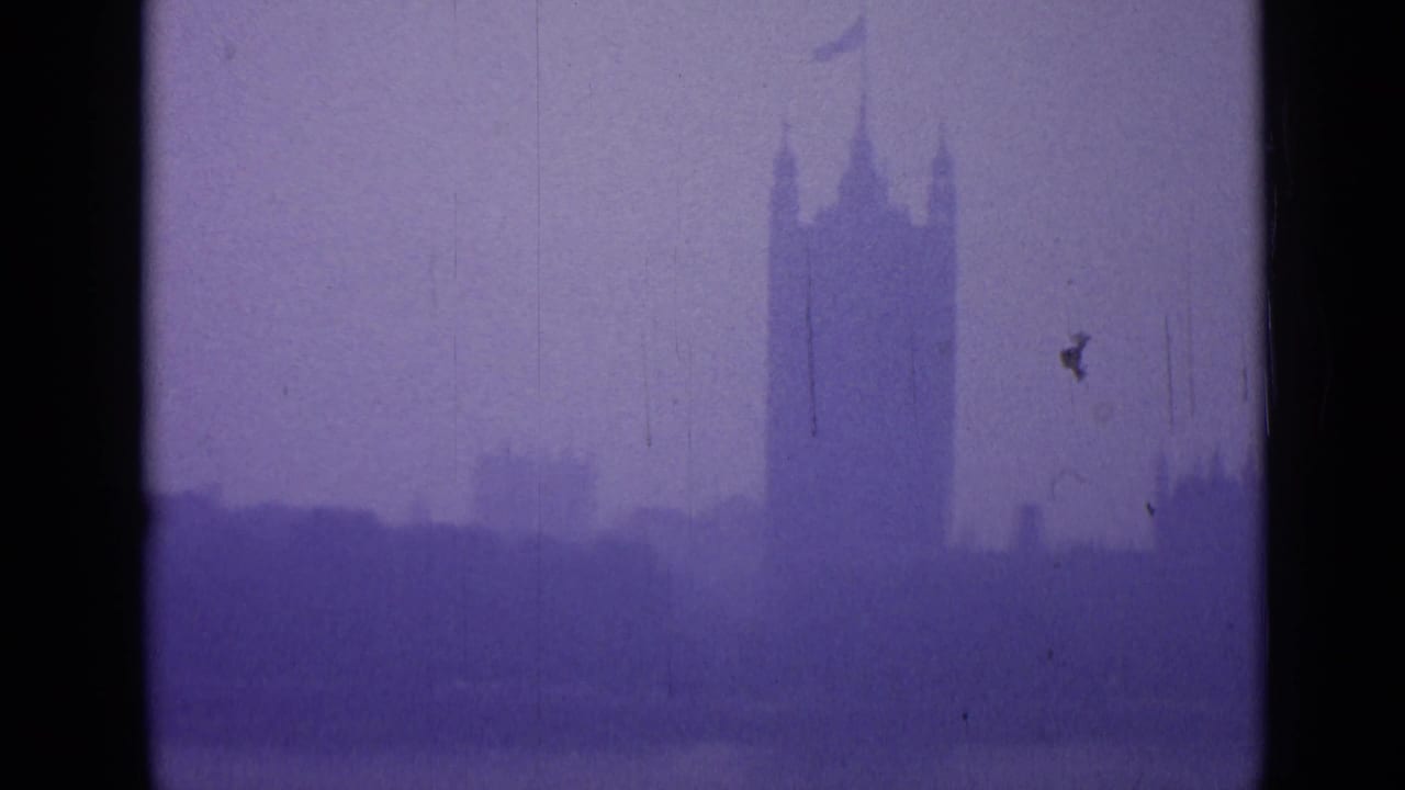 Hazy purple skyline with the Palace of Westminster tower silhouette and dark film gate edges.
