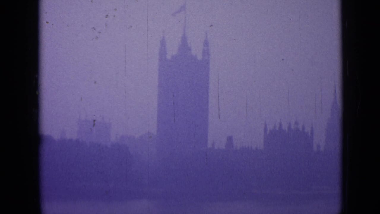 Distant Westminster skyline in haze, with tower silhouettes, purple tint and film wear marks.