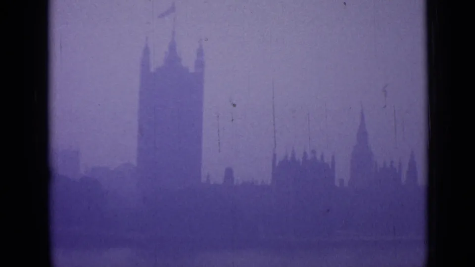 1962 London 8mm frame showing Westminster's silhouette across a dim foreground, with haze, grain and contact-sheet edge marks.