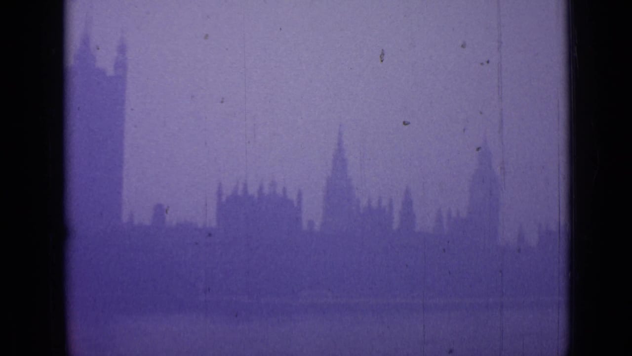 Foggy London skyline seen through dark vertical window bars.