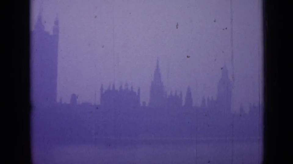 1962 8mm view of a faint London skyline and clock-tower silhouette partly obscured by fog and window framing.