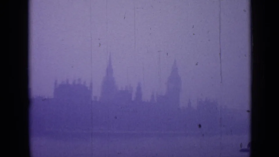 Fog-muted London skyline with a tall clock-tower form and nearby rooflines visible through aged 8mm color shift.