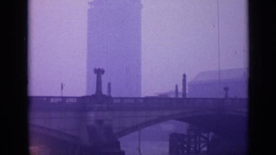 London riverside view with a stone bridge, river, tall background building, and misty purple-shifted 8mm texture.
