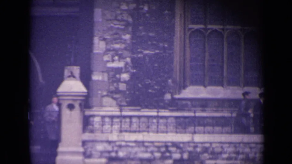 Late shot of the 1962 London street scene showing stone railings, Gothic-style windows, and uniformed boys partly at the frame edges.