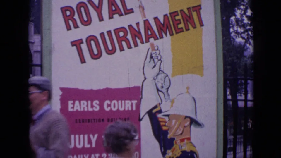1962 London home-movie view of a Royal Tournament Earls Court poster partly obscured by pedestrians.
