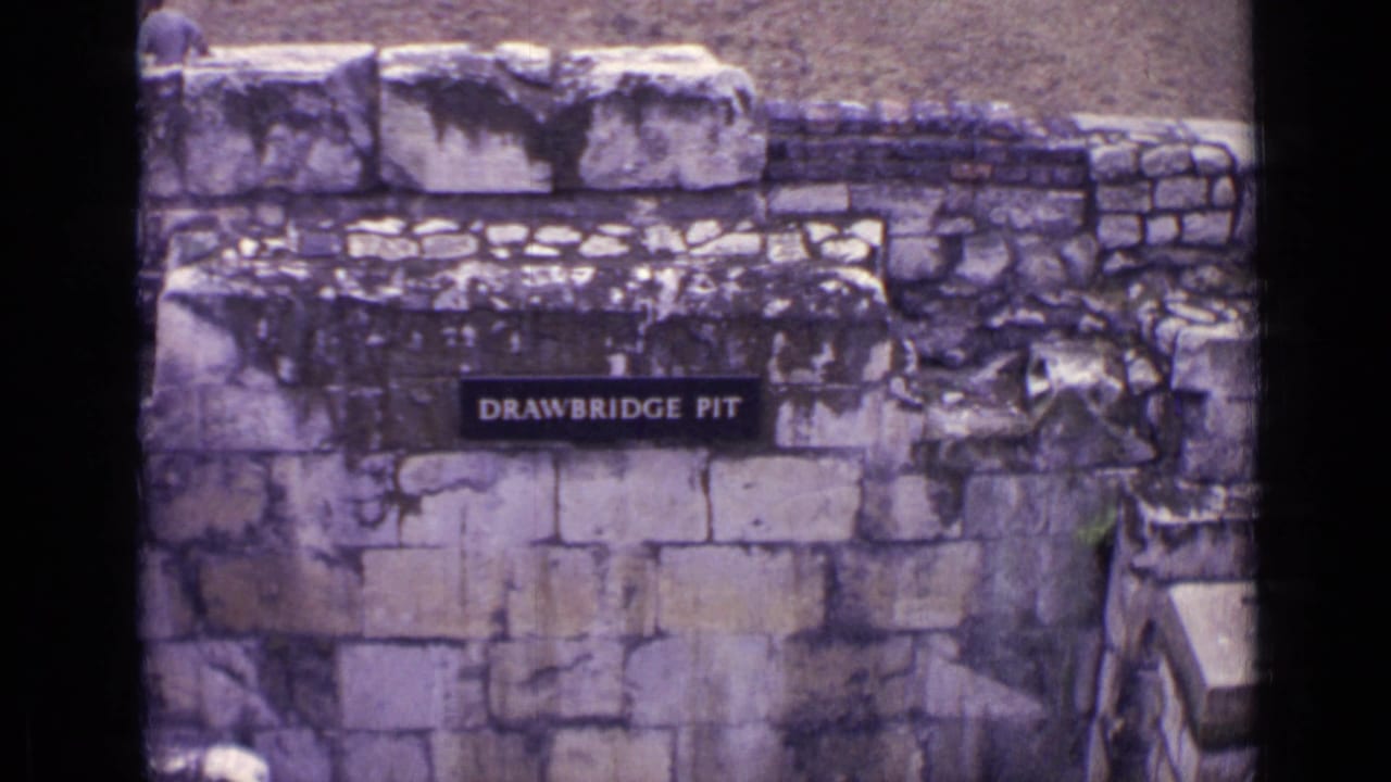 Stone wall at a London landmark with a visible Drawbridge Pit sign and dark film-frame edge.