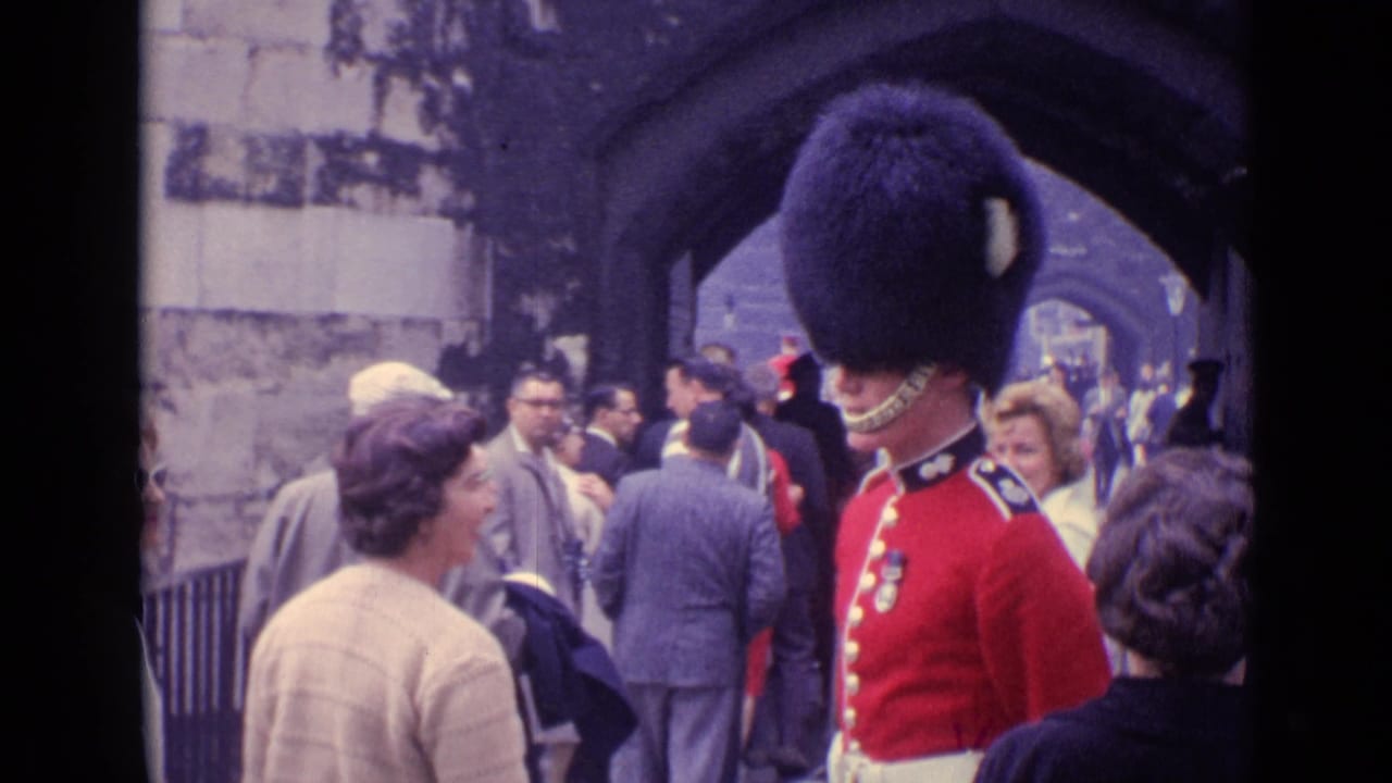 At the Tower of London, a ceremonial guard stands beside tourists entering through a stone passage.