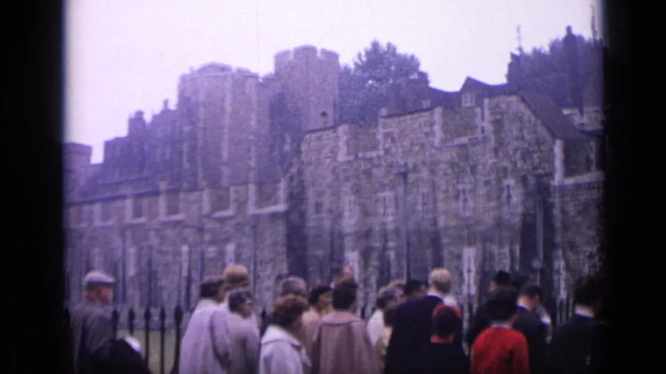 A wider 1962 London frame shows tourists in period dress below the Tower of London's stone walls and towers.