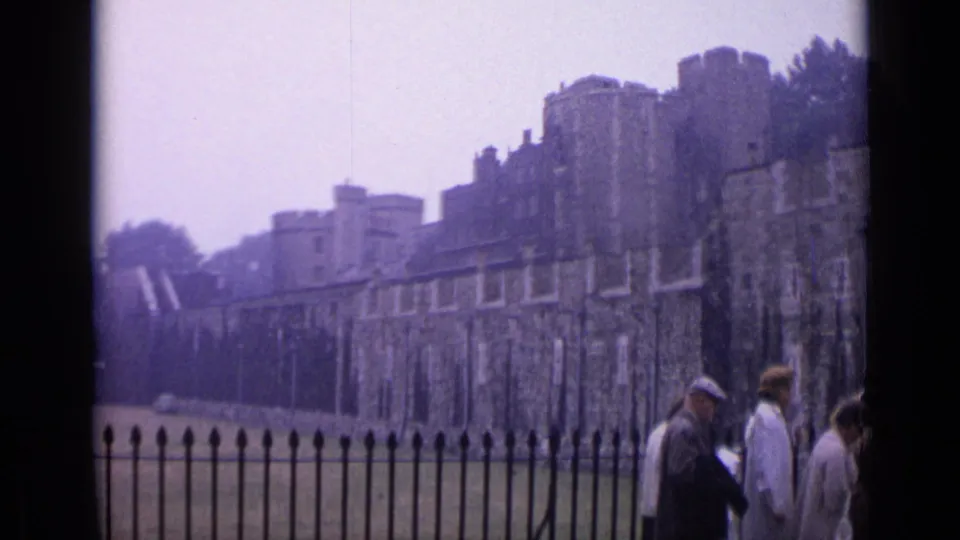 1962 London view of the Tower of London walls and lawn, with tourists partially visible near the frame edge.