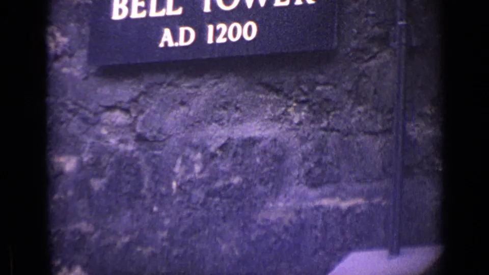 1962 London 8mm frame showing part of a Bell Tower A.D. 1200 sign on weathered stonework.