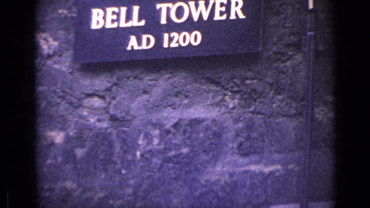 1962 London 8mm frame with a Bell Tower A.D. 1200 sign against textured historic stonework.