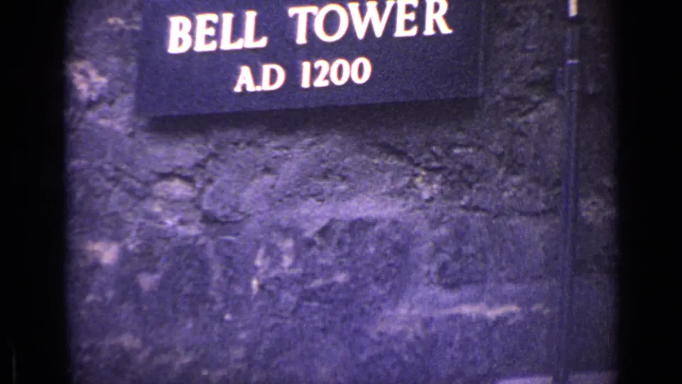 1962 London 8mm frame with a Bell Tower A.D. 1200 sign against textured historic stonework.