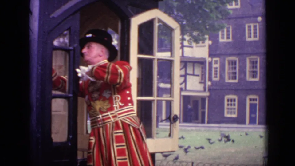 1962 London frame showing a ceremonial guard in red and gold uniform at an open doorway, with historic buildings visible beyond.