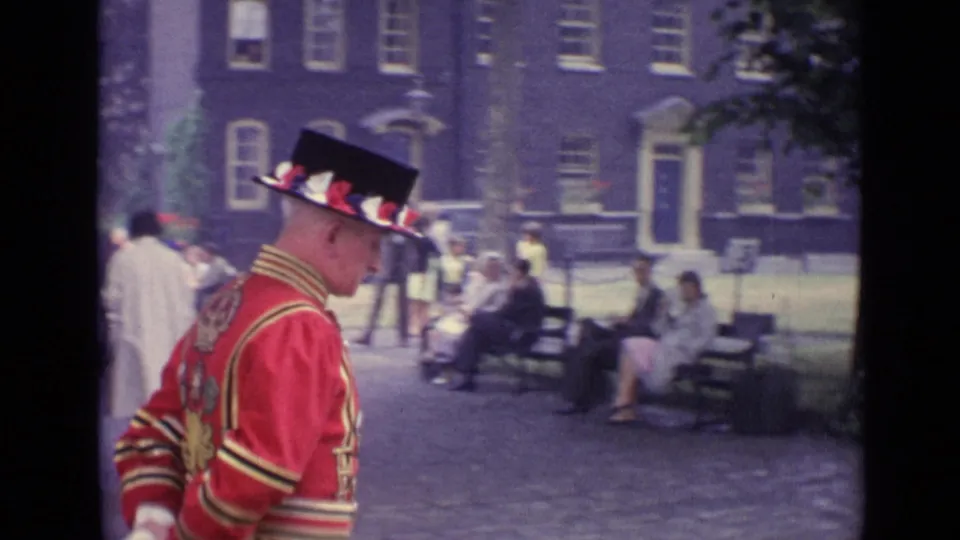 A side view shows the ceremonially dressed man walking across the courtyard, with seated visitors and buildings in the background.