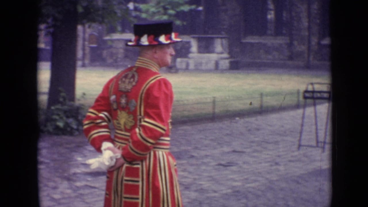 Red-uniformed man seen from behind near trees and a path.