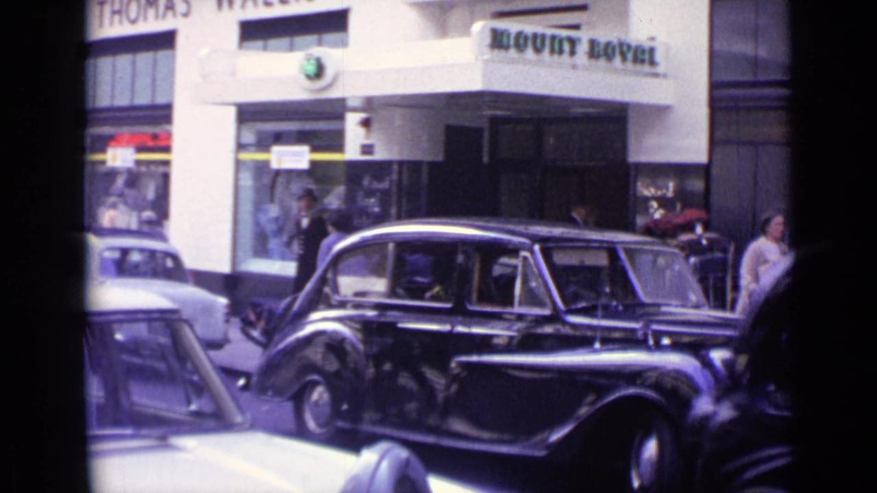 Black vintage limousine at curb with Mount Royal signage and pedestrians behind it.