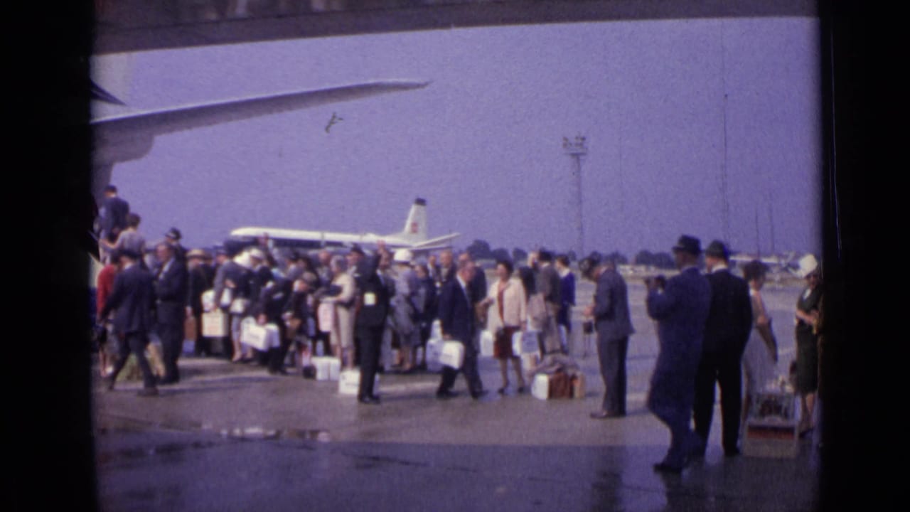 Crowd of passengers stands with luggage beside an aircraft on the tarmac.