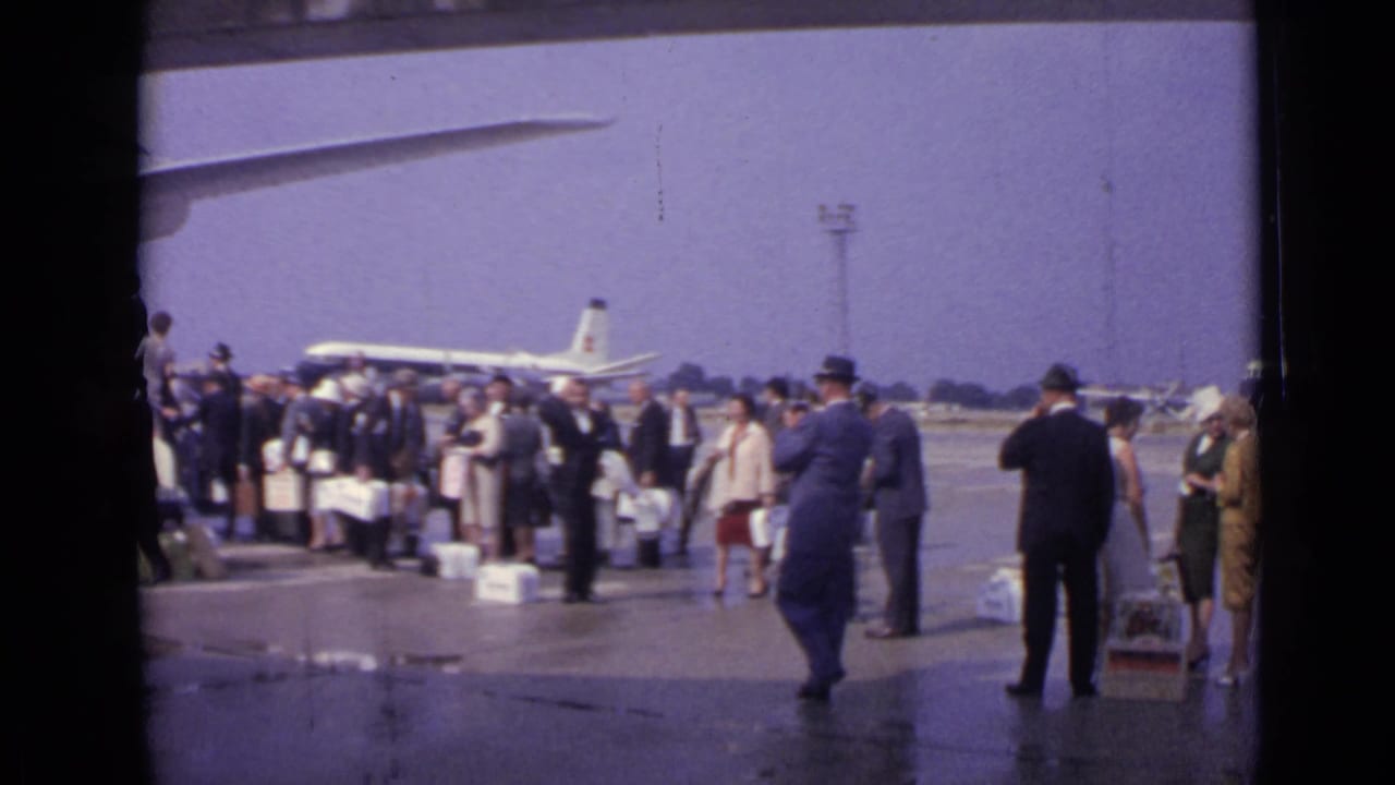 London 1962 airport footage showing travelers with luggage and uniformed personnel near a jet airliner on the apron.