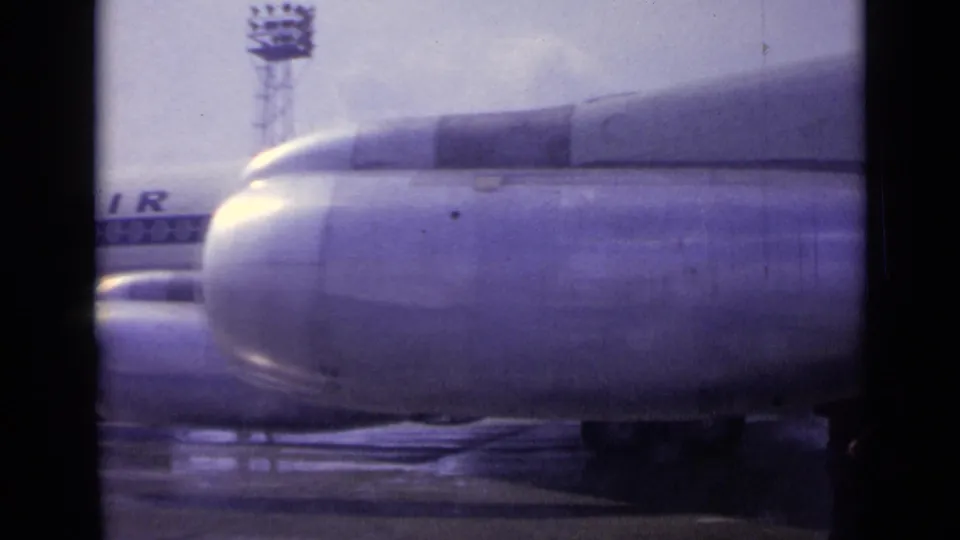 At the end of the pan, a large engine nacelle fills the foreground while partial airline lettering and the wet apron remain visible.