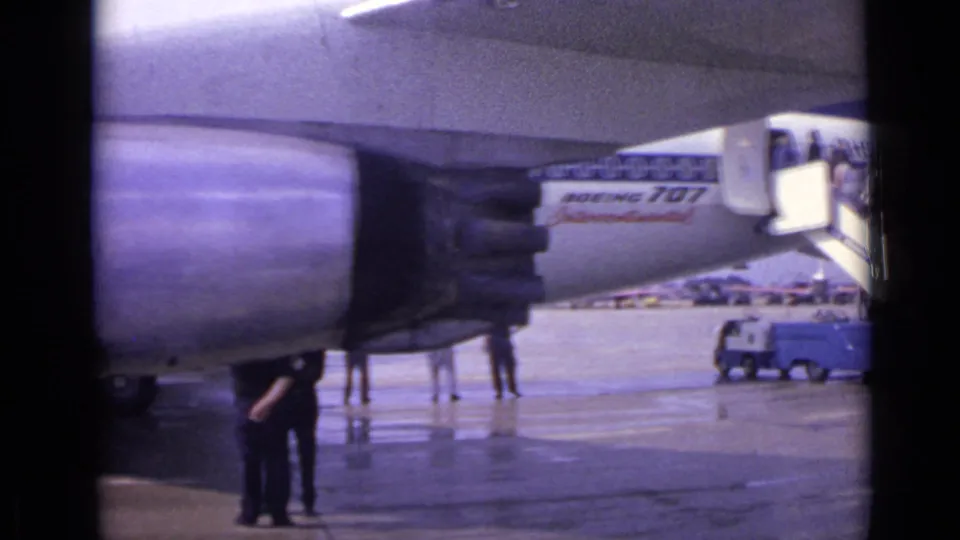 1962 London airport footage showing a jet engine, mobile stairs, wet tarmac, and passengers near a Boeing 707 Intercontinental.