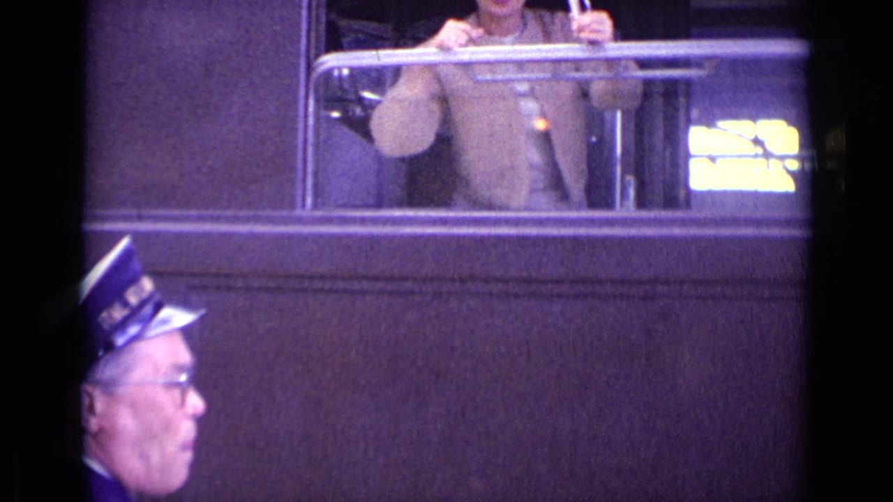 Uniformed man partly visible below a train window with a passenger above.