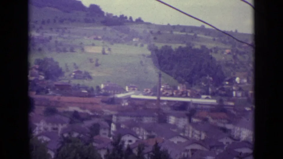 1962 Lucerne valley view from a cable car, showing houses, fields, trees, and an overhead cable through the gondola frame.