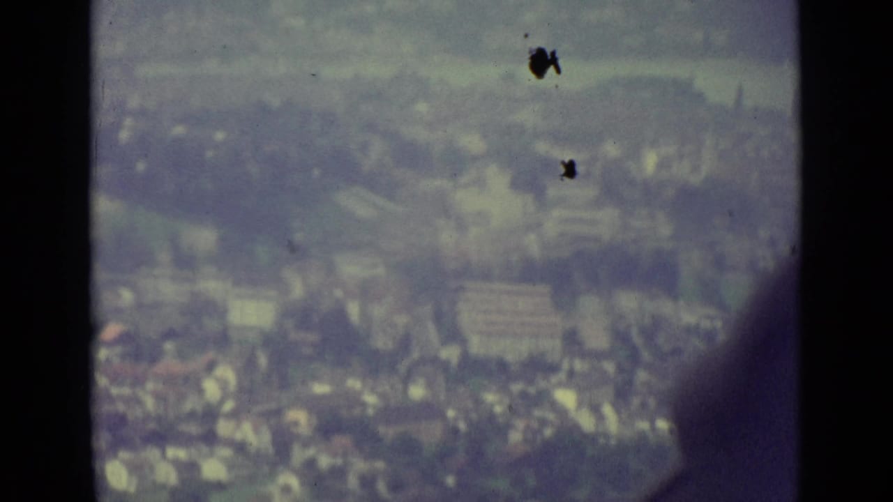 Hazy city view seen through dark cable-car window framing.