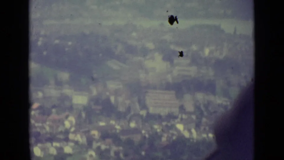 1962 Lucerne, Switzerland, seen from a cable car with dark window supports crossing a soft aerial city view.
