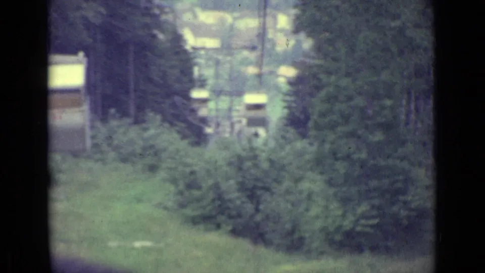 Lucerne cable-car footage from 1962 showing a wooded slope and small buildings below, framed by the moving cabin.