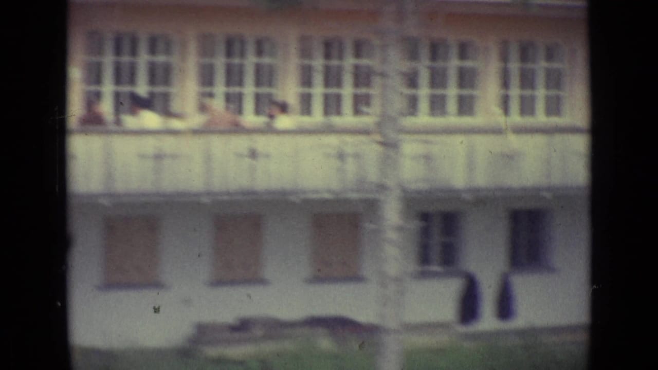 1962 home-movie frame near Lucerne showing a pale multi-window building facade, soft focus, and visible film gate edges.