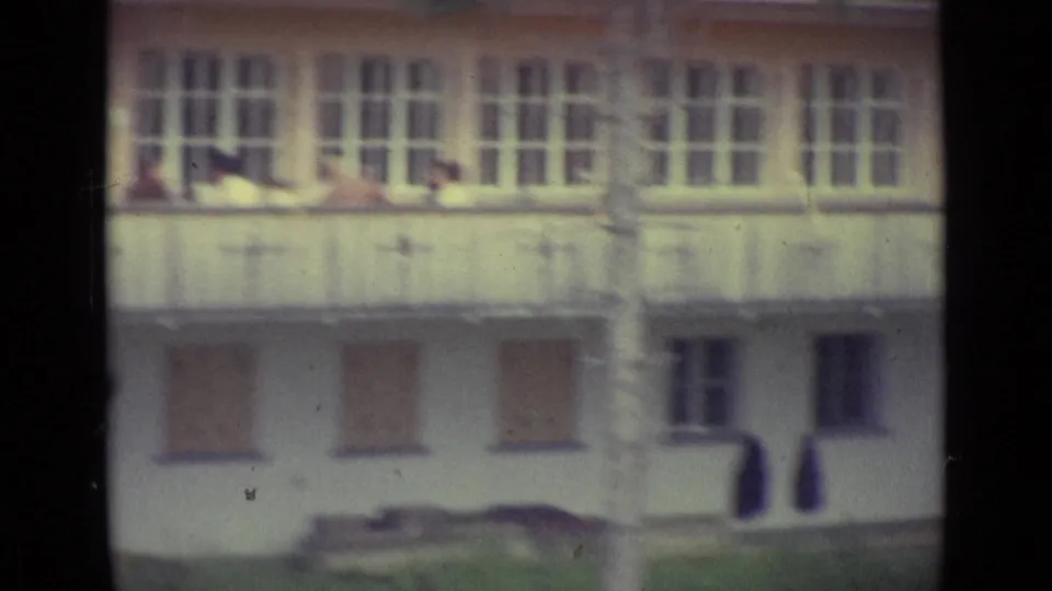 1962 home-movie frame near Lucerne showing a pale multi-window building facade, soft focus, and visible film gate edges.