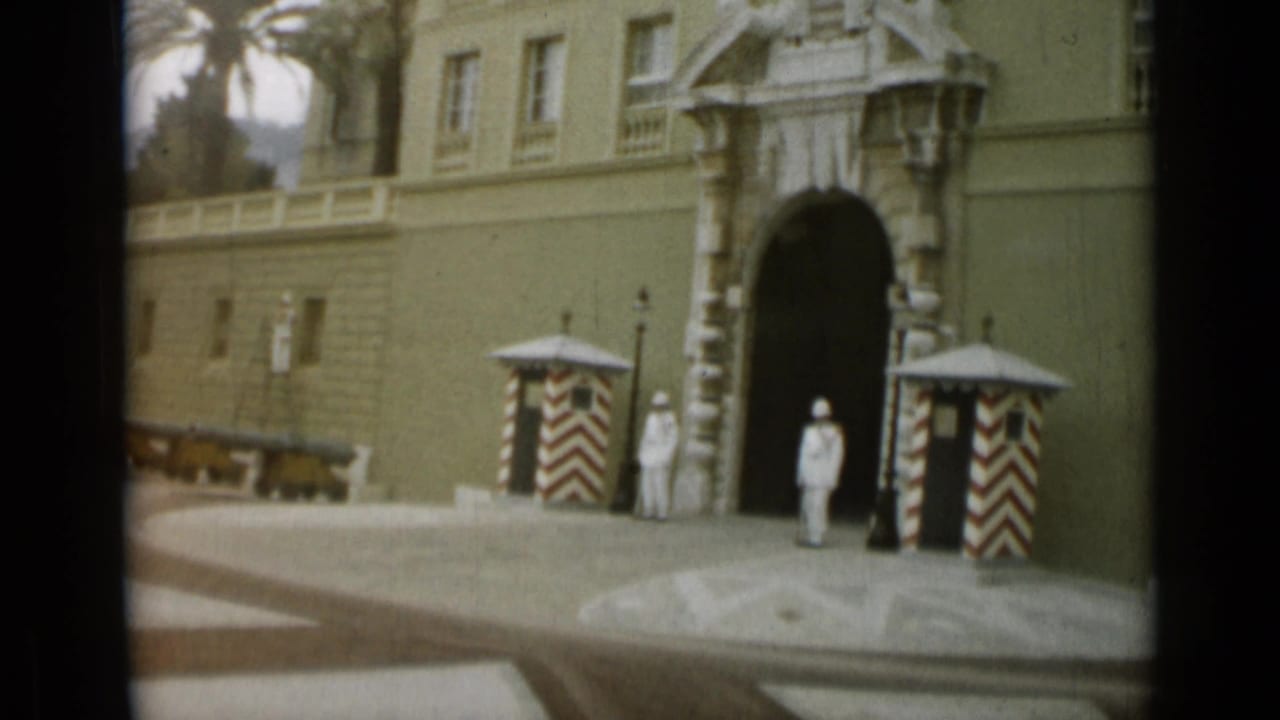 Guards stand near a large arched entrance with striped sentry boxes.