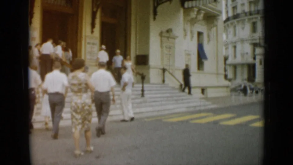 A visitor-shot 1962 Monaco view shows pedestrians approaching a formal entrance while a white-uniformed guard stands nearby.