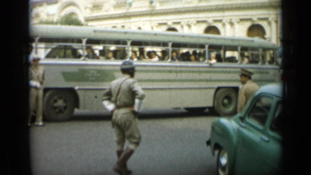 Uniformed officer near a passenger bus and green car on a Monaco street.