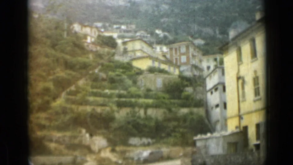 1962 Monaco frame with layered hillside houses, garden terraces, a pale yellow building, and soft 8mm color shift.