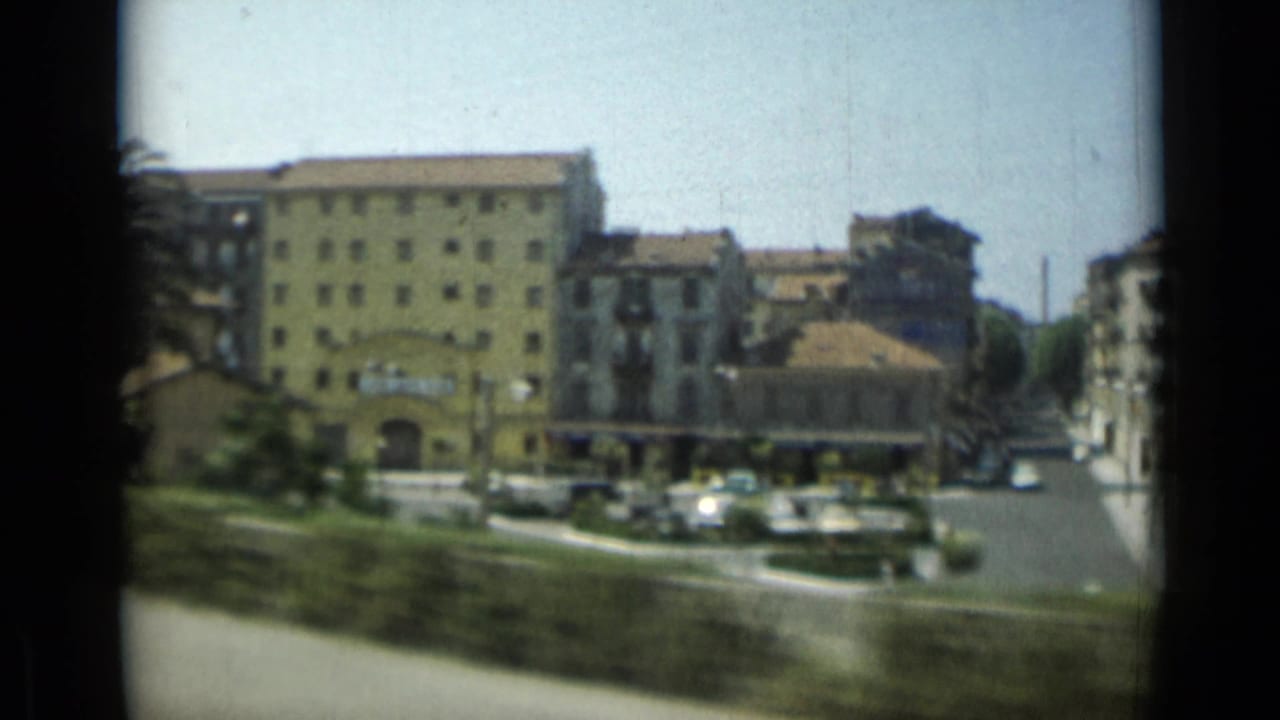 1962 Monaco travel footage showing a yellow apartment block, nearby street traffic, trees, and urban buildings from a moving vehicle.