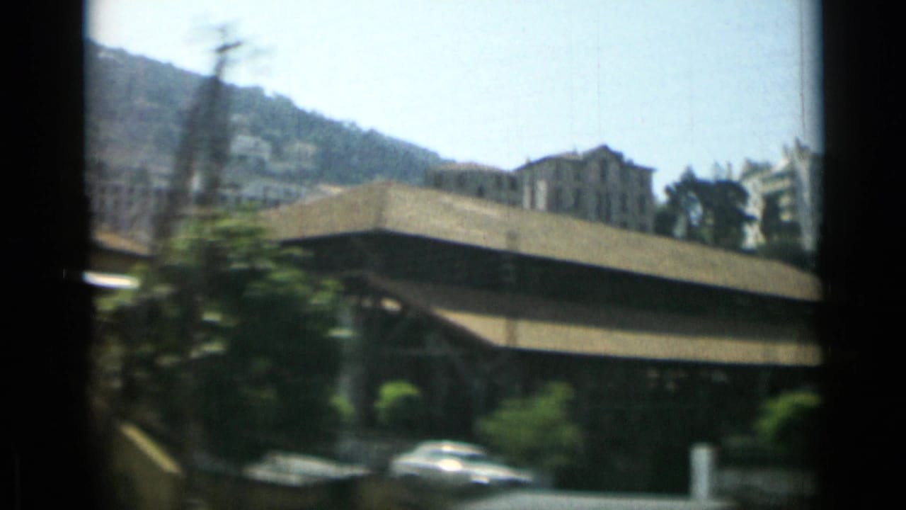 Blurred city buildings and hillside seen from a moving vehicle.