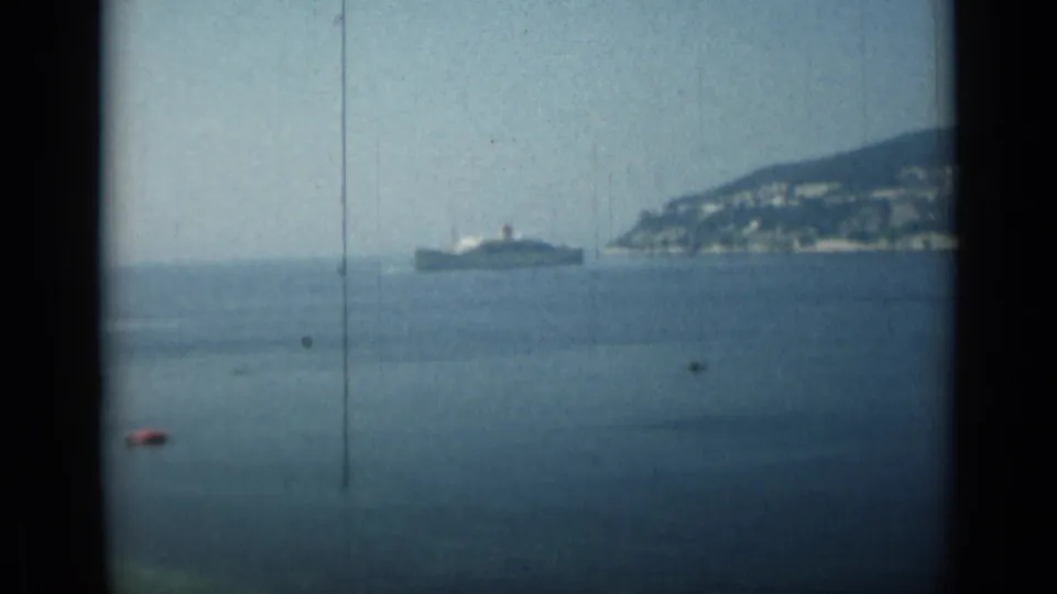 Monaco coastal view in 1962, with a distant ship on calm water and dark window or bridge edges framing the scene.