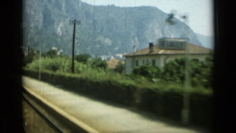 1962 Monaco rail-side view with platform, tracks, hillside, coastal villa, and distant Mediterranean water.