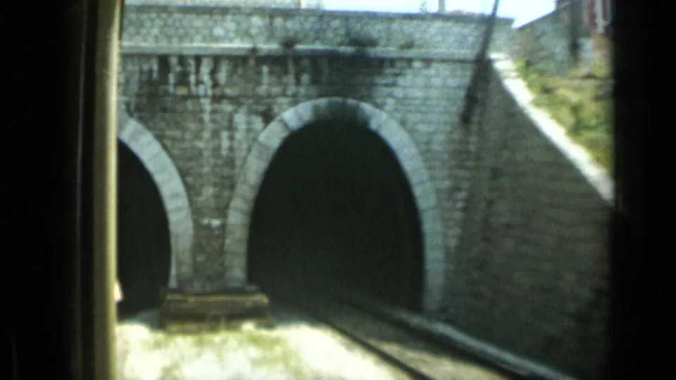 Close 1962 Monaco train-view frame of stone arches and a tunnel portal as the rail line enters the masonry structure.