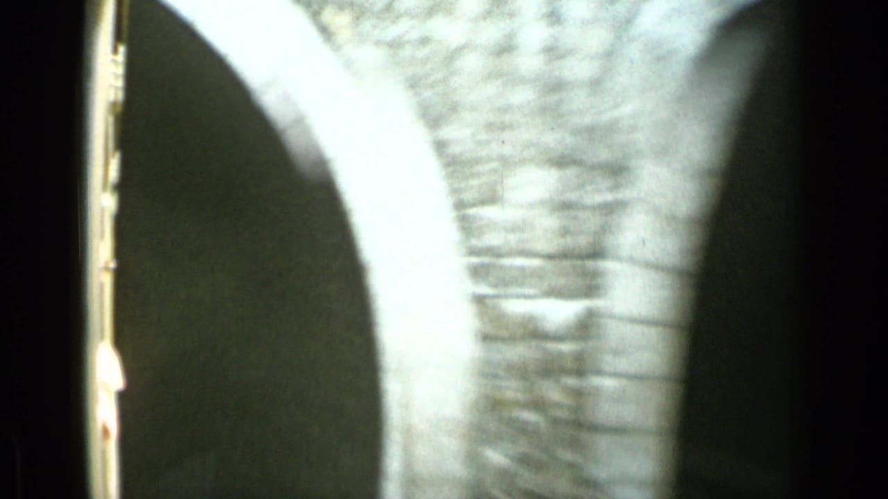 Moving view past a brick arch or tunnel wall beside railway tracks.
