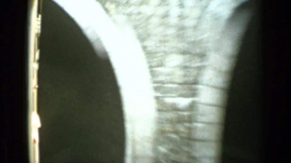 1962 Monaco home-movie frame from a moving train, showing a blurred brick arch or tunnel wall near the tracks.