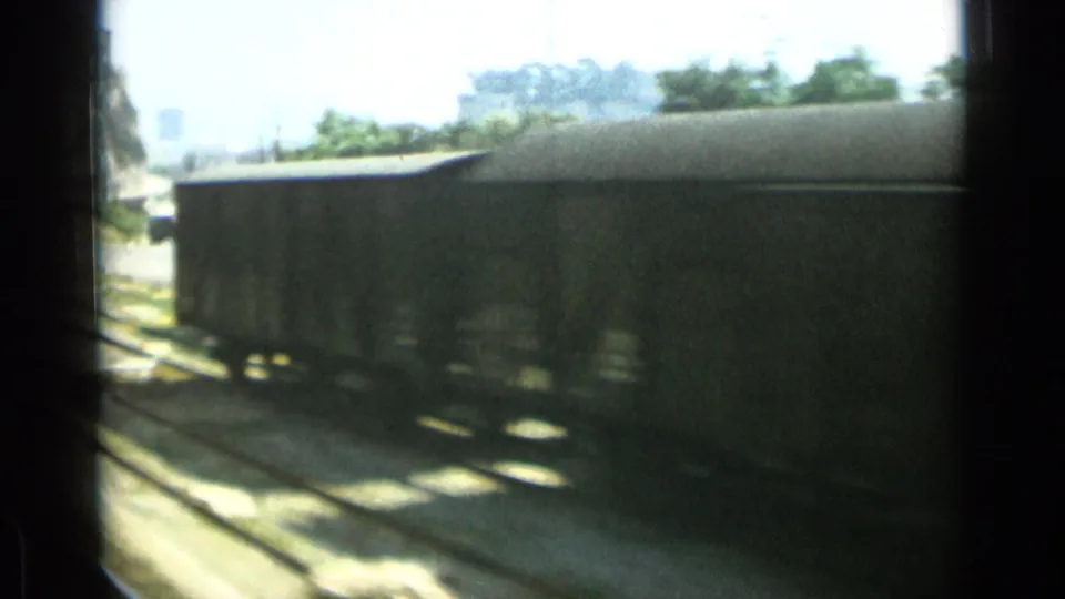 The Monaco rail sequence ends with a covered freight car passing the camera beside sunlit tracks.
